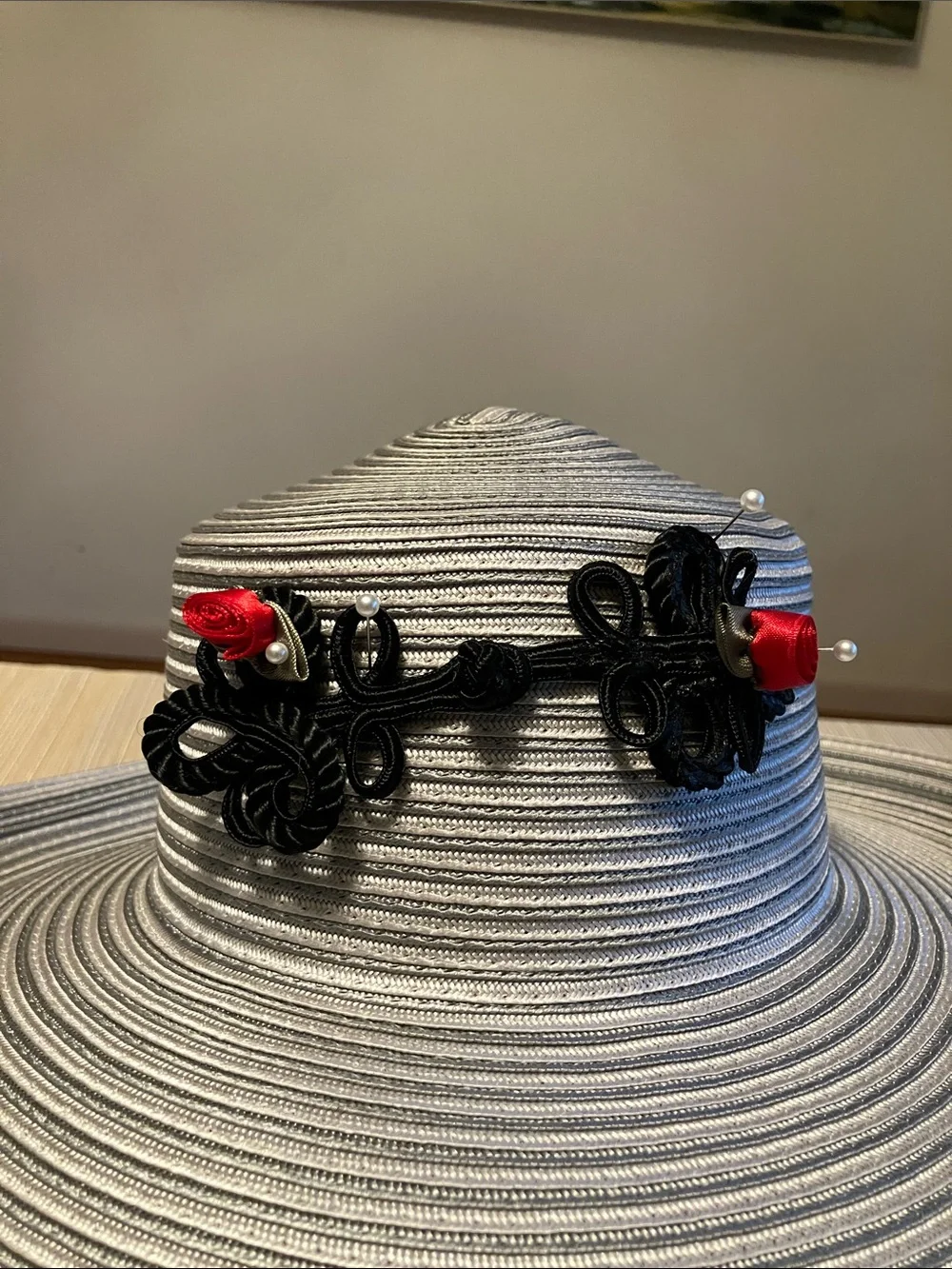 Wide Brim Straw Hat with Black Decorative Knot and Red Floral Accent